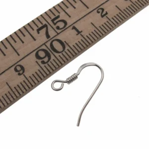 En Öronkrok med Spiral Sterlingsilver 17 mm örhängekrok är placerad bredvid en trälinjal som är markerad från 75 till 92 cm, vilket visar krokens kompakta storlek.
