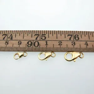 En karbinhake i förgyllt sterlingsilver 5x8mm visas under en trälinjal på en vit bakgrund, med längden tydligt markerad.