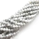 Flera trådar av runda, vita pärlor med subtil grå marmorering, arrangerade i en diagonal stapel mot en vit bakgrund.