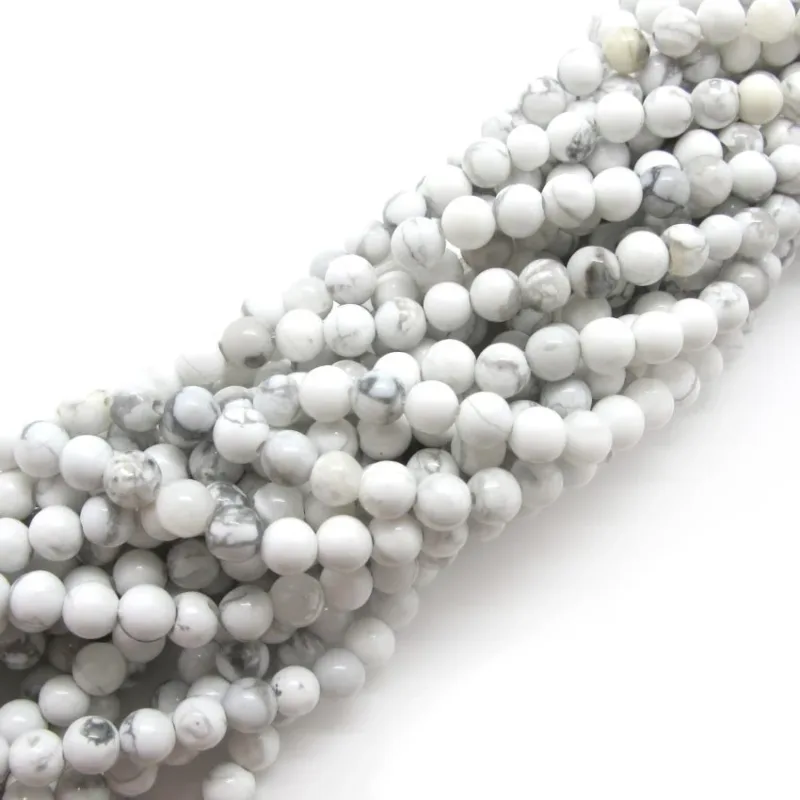 Flera trådar av runda, vita pärlor med subtil grå marmorering, arrangerade i en diagonal stapel mot en vit bakgrund.