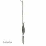 Ett Silverkedja ärtlänk YD 1,8mm - 10cm halsband har två fjäderhängen i olika längder. "Inspiration" visas i fet svart text nere till vänster på en vit bakgrund.