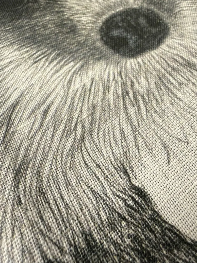 Närbild av Kökshandduk - Igelkott Henry, som visar dess strukturerade tyg med en detaljerad svartvit ögonillustration med strålande linjer. Kökshanddukens väv är synlig.