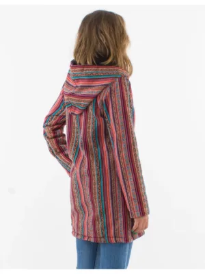 Sett bakifrån bär en person med vågigt hår Coline damjacka med fleecefoder - en lång, färgglad jacka med huva och vertikala ränder i rött, blått och orange - tillsammans med blå jeans.