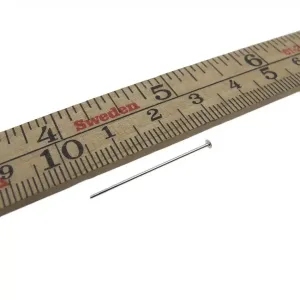 En Hattpinnar 25-50mm/0,51 metallnål i sterlingsilver är placerad bredvid en centimetermarkerad linjal i trä märkt "Sweden" i rött, vilket indikerar att nålens längd är cirka 3 centimeter.