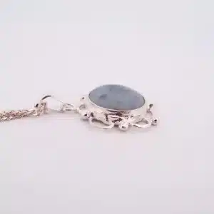 Silverhalsband med titeln "Halsband med handslipad Kalcedon 32x23 mm" med ett ovalt blågrått kalcedonhänge i en dekorativ silverram med pärldetaljer, mot en vit bakgrund.