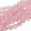 Närbild av flera trådar med runda, polerade rosa rosenkvartspärlor, arrangerade i lätt överlappande rader mot en vit bakgrund.