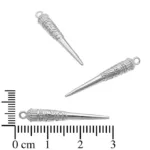 Tre Silverberlock - Etnisk design berlocker: utsmyckad, silverfärgad, konformad metall med övre öglor och dekorativa mönster, ca 3 cm långa. Visas bredvid en centimeterskala för storleksreferens.