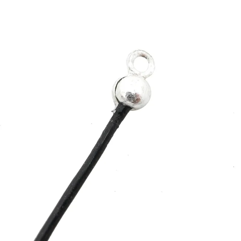 En närbild av Knutgömma sterlingsilver 3mm visar en svart sladd med ett litet runt ändlock i sterlingsilver med en ögla för fastsättning.