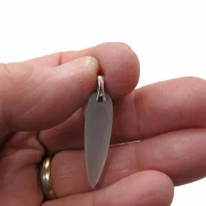 En hand håller ett genomskinligt ädelstenshänge med en Spetsögla U-formad ca 7,9x2,8 mm silverbygel. Bakgrunden är enfärgat vit och personen bär en guldring på fingret.
