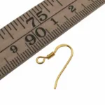 En Öronkrok förgylld med spiral 19mm visas bredvid en trälinjal, vilket indikerar att den guldfärgade örhängekroken mäter cirka 2 centimeter i längd.