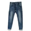 Cozy elastisk byxa - Jeans är blå denimjeans med upprullade muddar, stora påsydda framfickor, synlig knapp och linning, platta mot vit bakgrund.