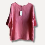 Linneblus - ELBA är en löst sittande rosa linneblus med trekvartsärmar som visas på galge mot en enfärgad bakgrund. En vit etikett är fäst vid kragen.