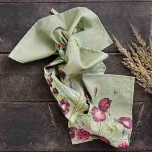 Light green scarf with pink and purple floral pattern laid on a dark wooden surface, with dried grass on the right.