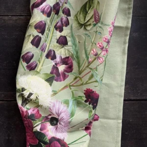 Close-up of light-green fabric with a vivid botanical print featuring purple and pink flowers and green stems.