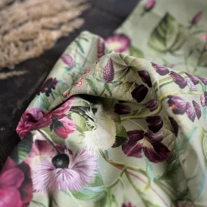 Close-up of pale green floral fabric with pink, purple, and white blossoms folded over a dark surface.