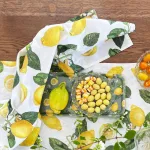 Lemon-pattern table setting with a glass tray holding a large lemon and small yellow potatoes, plus orange-striped candies.