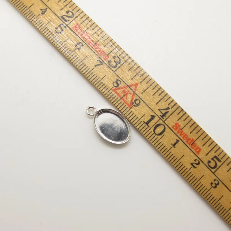 Wooden measuring ruler with black marks and red markings, placed diagonally on a light background, with a silver pocket watch at bottom left.