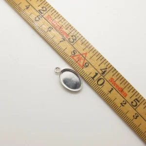 Wooden measuring tape laid diagonally with centimeter marks and red highlighted sections on a light background, small metal rings visible nearby.