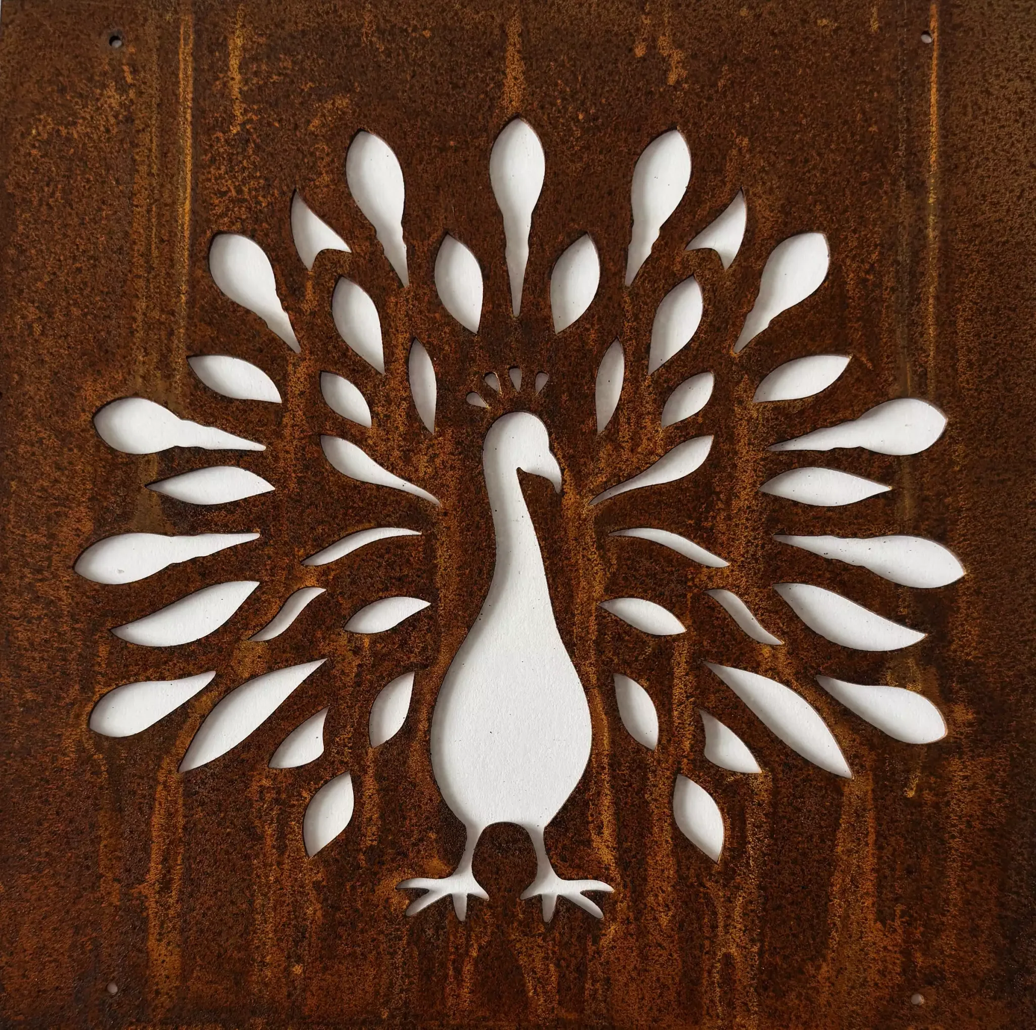 Rusted metal sheet with a white floral cutout pattern radiating from center, creating a flower motif.