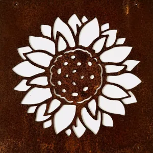 Close-up of a white floral cutout (lotus-like) against a rusted metal surface, showing intricate petals and dotted center pattern.