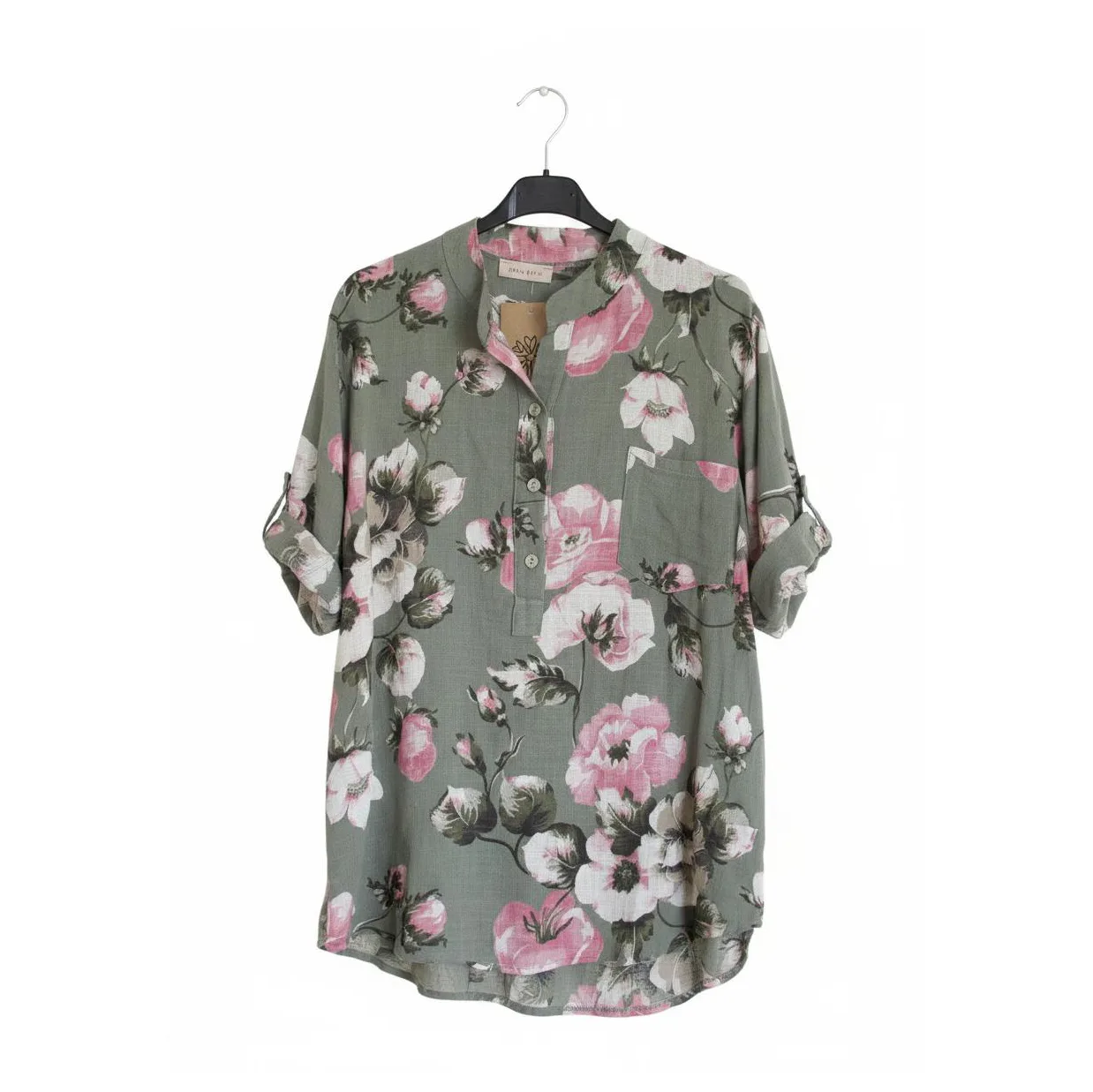 Green-gray floral tunic blouse on a hanger with pink and white blossoms.