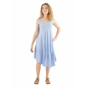 Woman in light blue sleeveless dress with embroidery, standing with one hand on hip and smiling as she looks to the side.