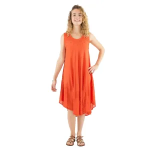 Woman wearing an orange sleeveless midi dress with a flowy skirt, standing with one hand on hip, sandals on feet.