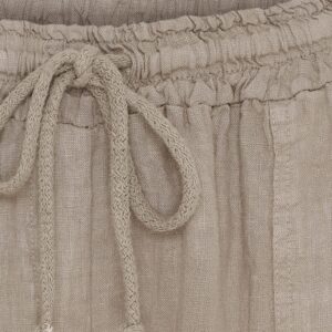 Close-up of beige woven fabric with braided drawstrings tied in a knot and vertical pleats.