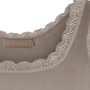 Close-up of beige fabric with decorative lace trim along the edge; a small tag reading 'MARTA' is visible.