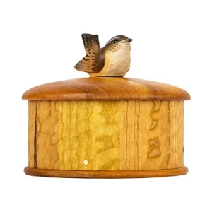 Wooden cylindrical birdhouse with a small brown bird perched on the roof.
