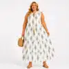 Plus-size woman wearing a white sleeveless maxi dress with a damask-style pattern, carrying a woven straw handbag.