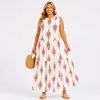 Woman wearing a sleeveless white maxi dress with red geometric floral pattern, holding a straw handbag and wearing sandals in a neutral studio.