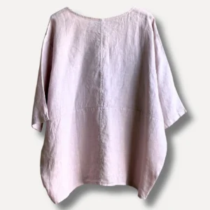Back view of a light pink linen blouse with loose sleeves and a center seam running down the back.