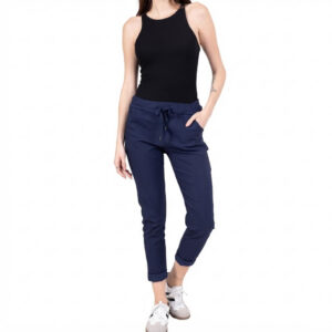 Full-body view of a woman in a black sleeveless top, navy jogger pants with rolled cuffs, and white sneakers.