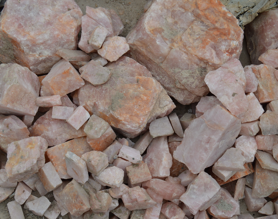 IMG_2222 - Fredrix Design & Smyckerian Pile of pink rose quartz rocks and broken stones scattered on dusty ground.